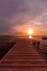 Wooden pier on a warm light during sunset, with violet and orange sky