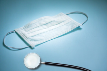 protective face mask and stethoscope on blue background