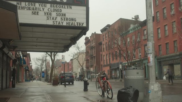skateboarder rides past movie theater marquee in Brooklyn during Corona quarantine