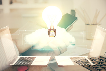 Double exposure of man's hands holding and using a digital device and bulb hologram drawing. Idea concept.