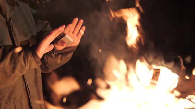 man in military uniform warms up by the fire