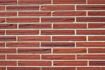 Vintage red color brick wall background with textured striped bricks in a 1/3 offset brickwork pattern