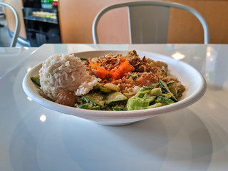 Spicy ahi tuna and salmon poke bowl, filled with avocado, mixed greens, rice