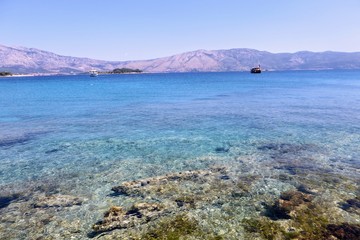 A water level view of the beautiful clear waters of Lumbarda Beach on Korcula Island, Croatia.  The peljesac peninsula is in the background.  The adriatic sea has some of the most beautiful colors.