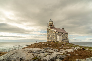 Fototapeta na wymiar Historic lighthouse, stone building double storey, slate roof and sash window, a walkway around the light room gives the impression of a citadel, sits on a rocky shore of the Atlantic ocean