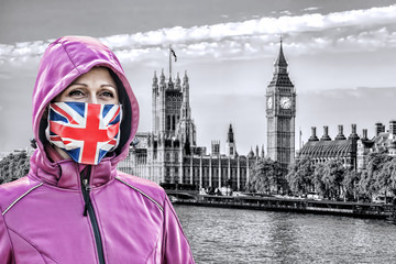 Woman wearing protection face mask with British flag against coronavirus in front the of Big Ben, London, England