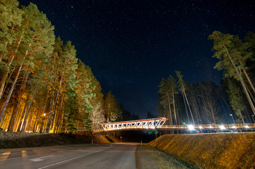Landscape at night, sky full of stars over a asphalt road with a wooden bridge (high ISO photography)