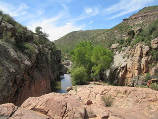 View over a cliff on the Water Wheel Falls hiking trail in Payson, Arizona, with Ellison Creek running below