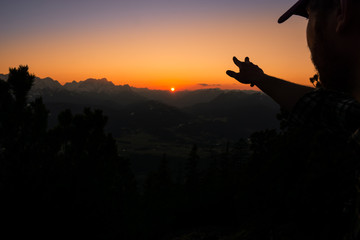 Person zeigt in Richtung Sonnenuntergang in den Alpen im Karwendel