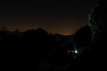 Stirnlampe leuchtet in den Sternenhimmel in den Alpen