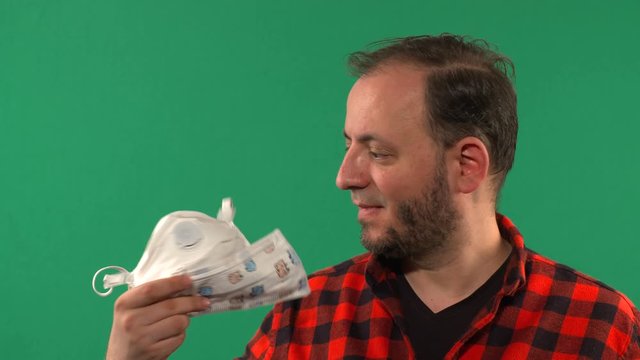 Close Up Of a Man With A Medical Mask Filmed On Chroma Key. Man Wearing Hygienic Mask. Coronavirus Protection Covid - 19. Portrait Of Medical Doctor Putting Mask On Green Background. 4K video