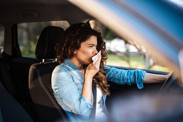 Young woman coughing while driving car. Healthcare, virus, allergy concept.