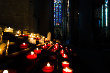 Flaming candles in a medieval church with stained glass windows