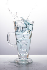 Splash of water in a glass from an ice cube falling into a glass