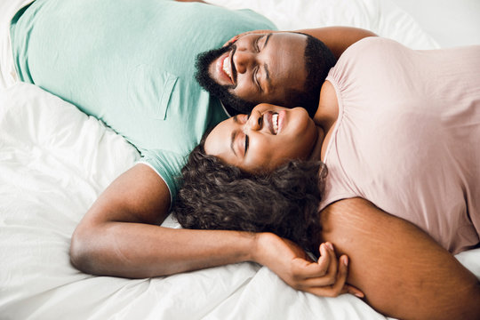 Pleased young couple lying in bed and smiling stock photo