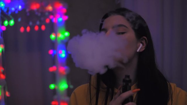 Girl smoking vape, vaping teenager, e-cigarette, inhaling vaping device.