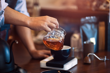 Barista hold dip glass and pouring a hot coffee after dip coffee in a glass cup of coffee.