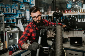 Fototapeta na wymiar Young beard bicycle mechanic repairing bicycles in a workshop..