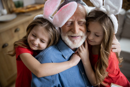 Loving Girls Hugging Their Grandpa Stock Photo