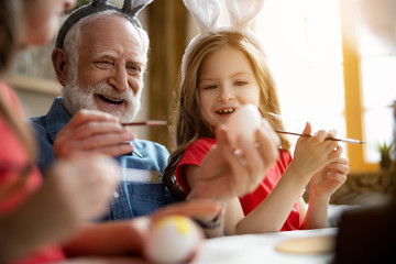 Excited grandfather and granddaughter painting eggs stock photo