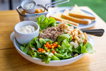 salad with tuna, salad dressing in bowl on the table.