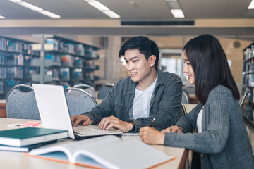 High school or college students studying and reading together in library. Student use laptop at library.