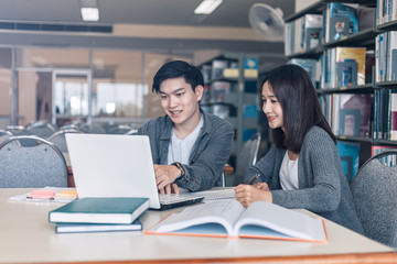 High school or college students studying and reading together in library. Student use laptop at library.