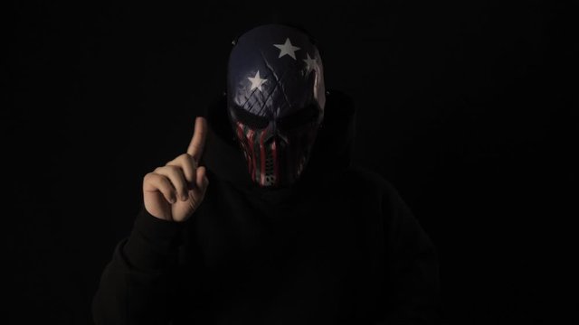 Man in a scary mask USA flag color bangs his head