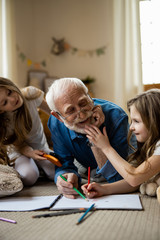Twin girls having fun with mirthful grandfather stock photo