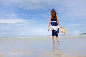 Woman barefoot walking on summer along wave of sea water and sand on the beach.