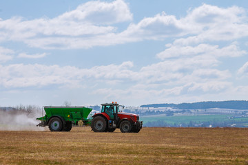 Tractor spreading fertilizer on grass field. Agricultural work.