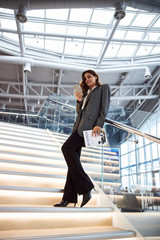 Pretty lady standing on stairs and using smartphone