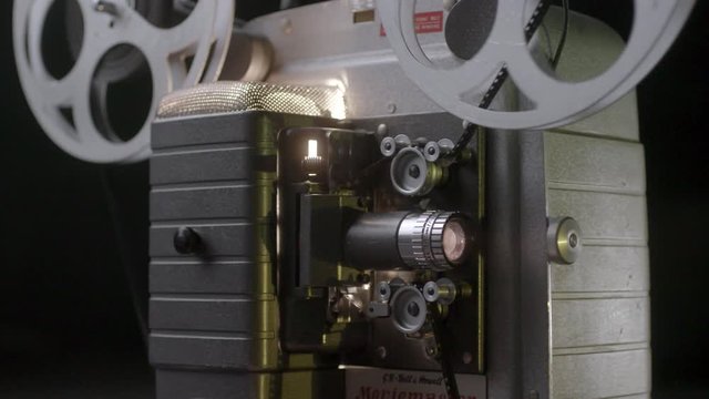 Vintage 8mm cine projector turning on, shot from the side.
