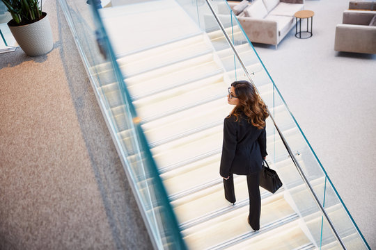 Stylish young woman climbing stairs in business center