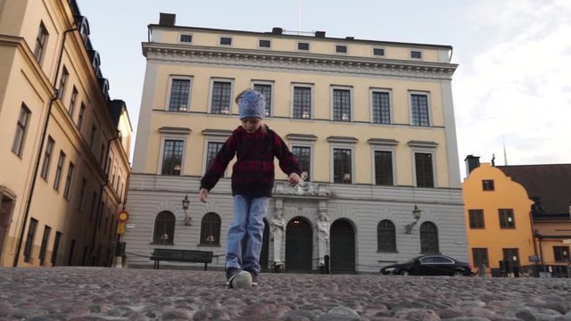 Stockholm old town Gamla Stan Slottsbacken street little child girl playing with a cobblestone
