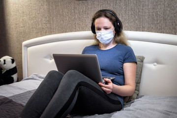 Woman in face mask working with laptop staying home. COVID-19 corona virus quarantine concept