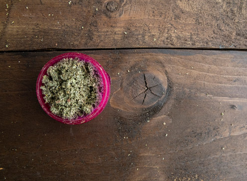 Political and world view debate question around alcohol and cannabis marijuana use. Ground up bud in a blue glass pipe and a bright pink grinder 