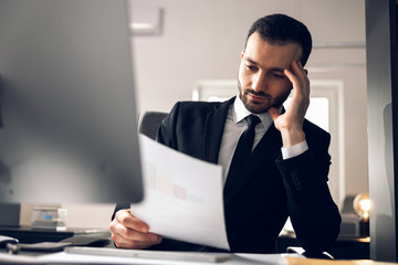 Concentrated Caucasian man reading documents in office