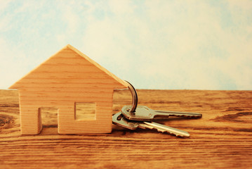 House key on the background of a wooden trinket in the shape of a house, the concept of moving or renting out property, planning the purchase of a house for real estate investment.