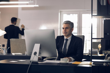 Mature office worker in suit working at computer indoors