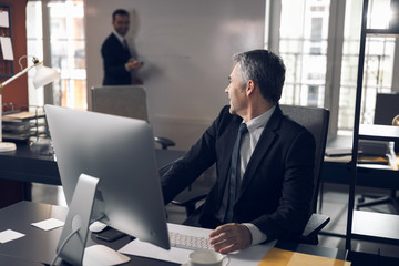 Serious office worker in suit talking to his colleague indoors