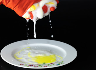 Scouring sponge foaming gloves and yellow cleaning cloth. The foam in the sponge is dripping. In black background. Close up.