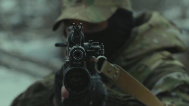 Soldier aims from a machine gun directly at the camera. 