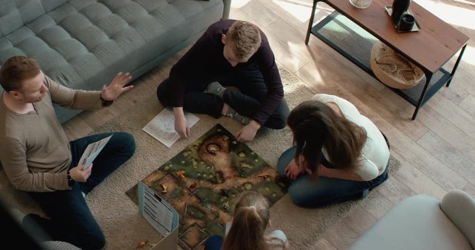 OVERHEAD Family - father, mother and two kids playing a board game together. Stay home, quarantine. Board game is custom made for the shot. RED Dragon