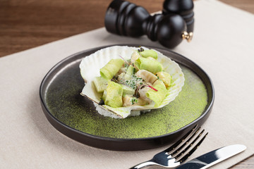 Scallop salad with avocado, served in a shell ? luxury delicatessen starter in a restaurant