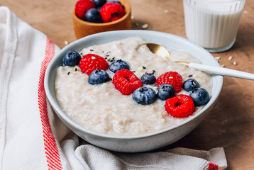 Breakfast oatmeal porridge with fresh berries and almond milk. Healthy vegan food concept. Top view. Copy space. Flat lay