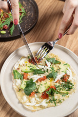 Young woman is eating a flatbread with vegetarian filling: chinese cabbage, sprouts and tomatoes