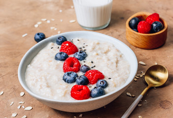 Breakfast oatmeal porridge with fresh berries and almond milk. Healthy vegan food concept. Top view. Copy space. Flat lay
