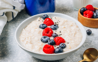 Breakfast oatmeal porridge with fresh berries and almond milk. Healthy vegan food concept. Top view. Copy space. Flat lay