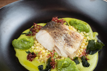 Cod fillet baked with avocado puree and israeli ptitim, close up